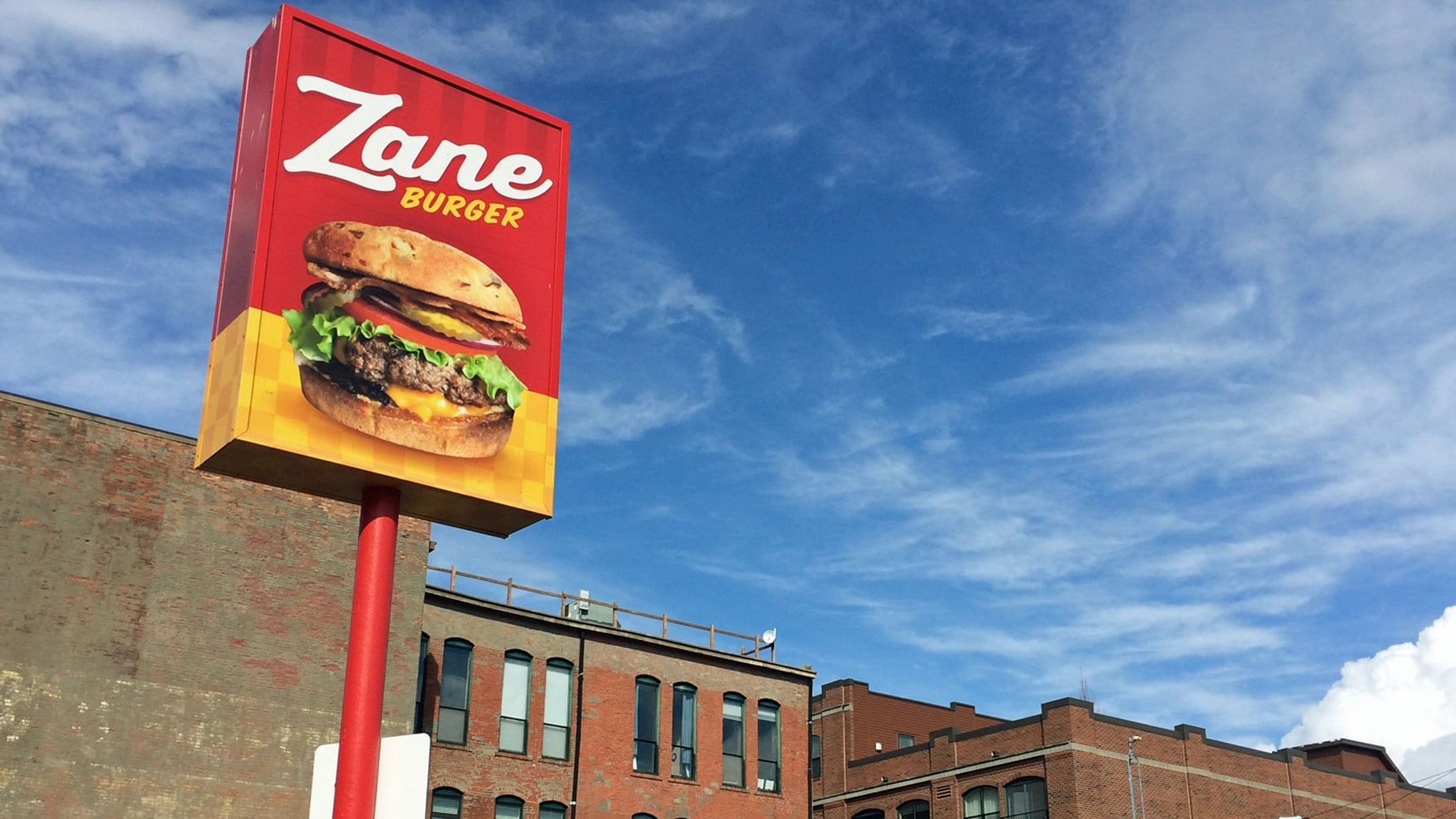 A zane burger sign is in front of a brick building.