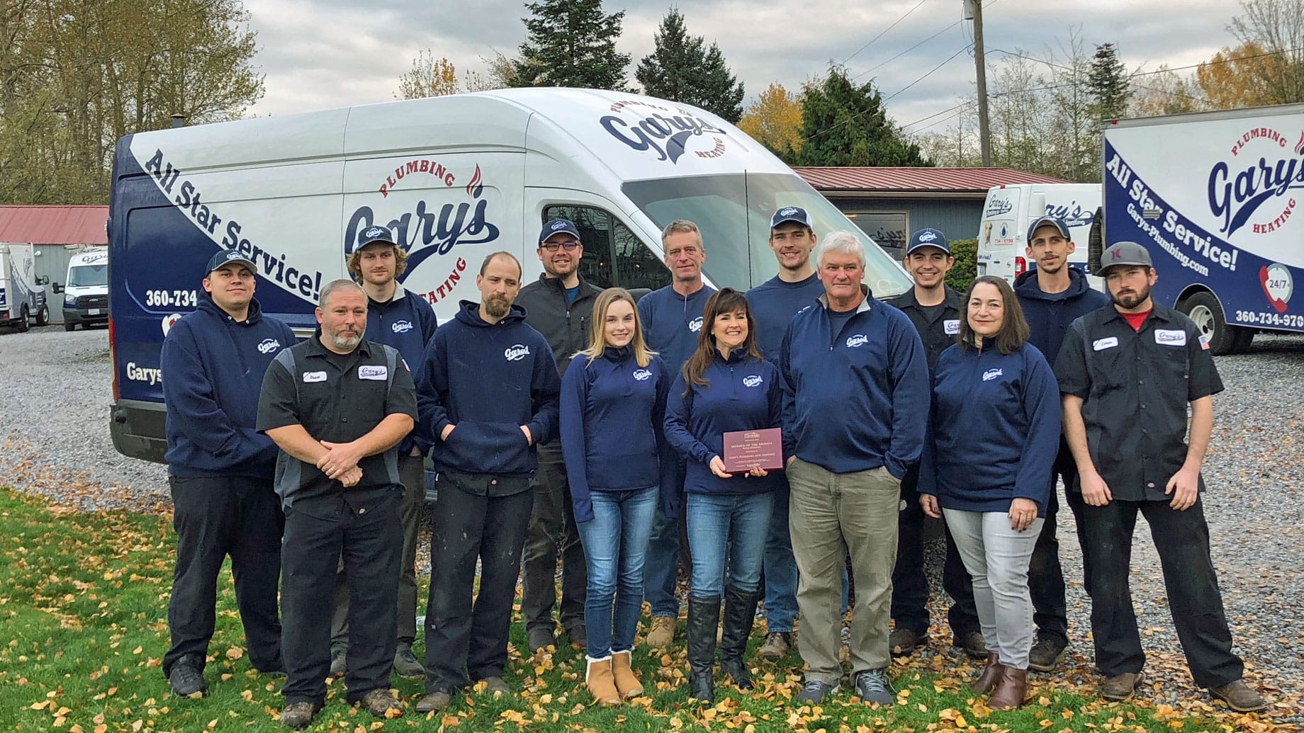 A group of people are posing for a picture in front of a van.