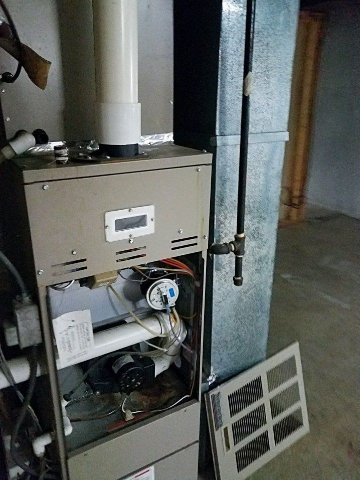 A furnace is sitting in a basement with the door open.