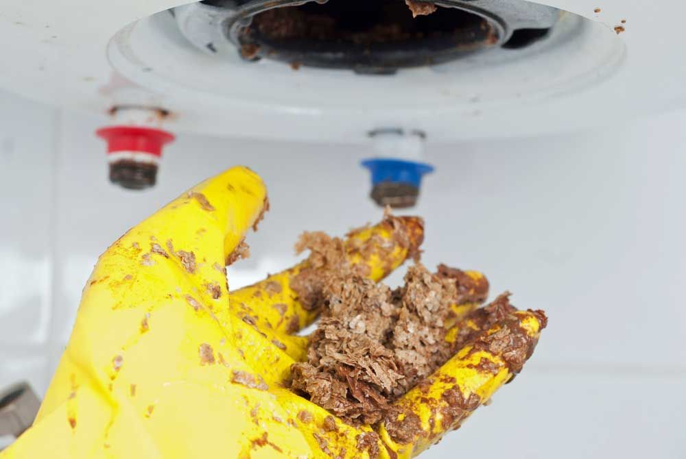 A person wearing a yellow glove is holding a piece of rusty metal.