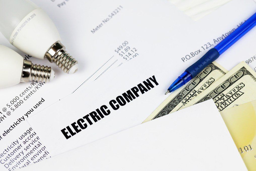 An electric company bill with a pen and money on it