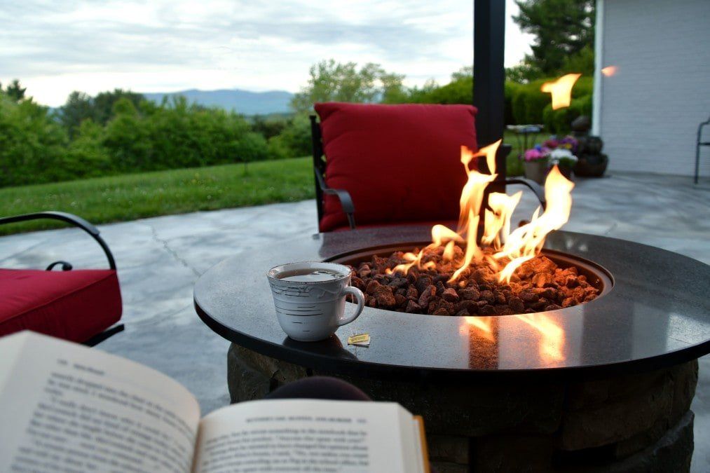 A fire pit with a cup of coffee and an open book