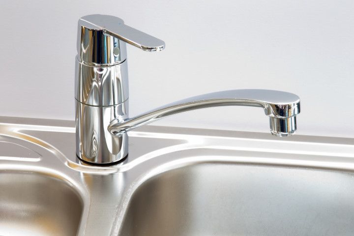 A close up of a stainless steel kitchen sink with a chrome faucet.