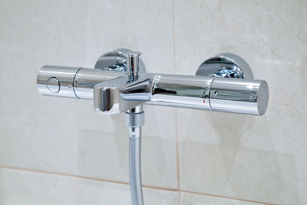A close up of a shower head and faucet in a bathroom.