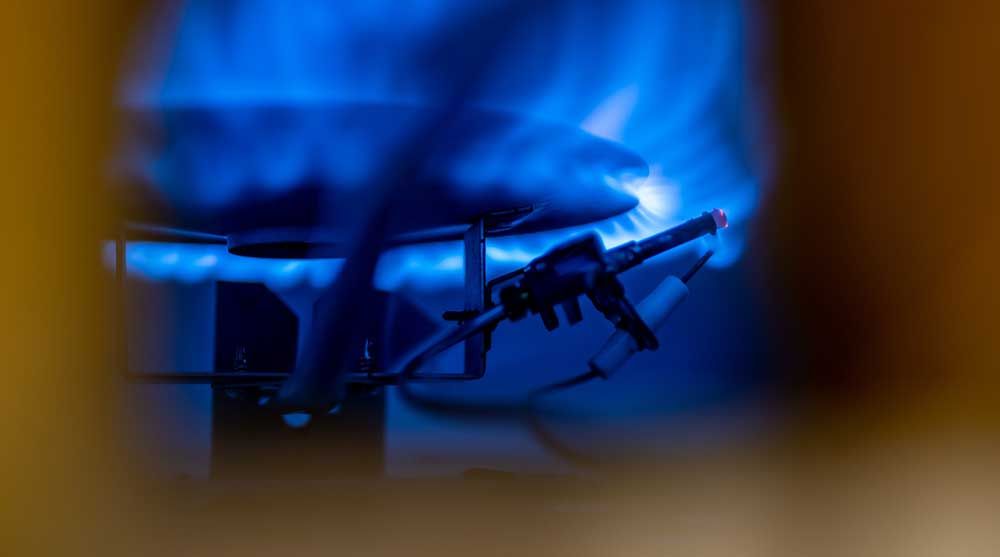 A close up of a gas burner with blue flames coming out of it.