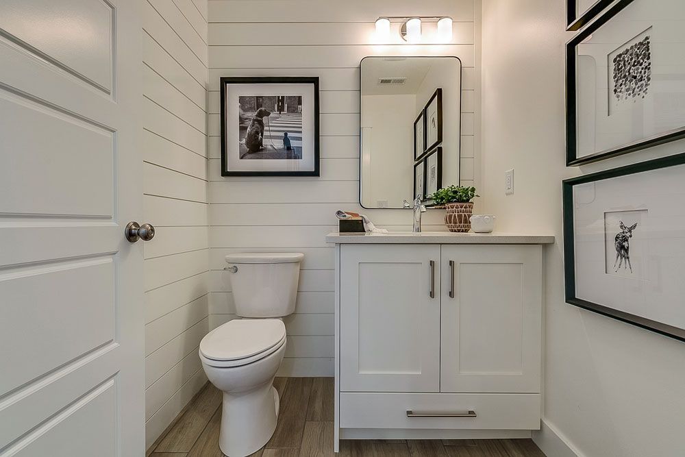 A bathroom with a toilet , sink and mirror.