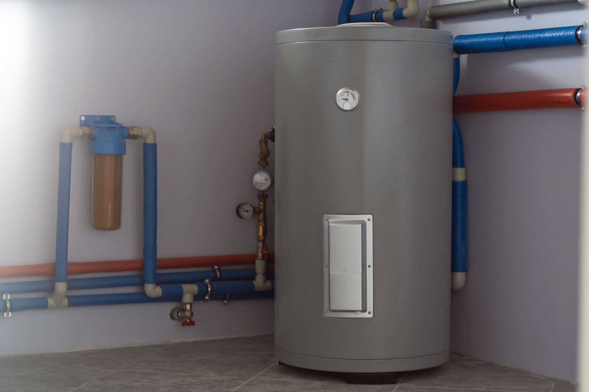 A large gray water heater is sitting in a corner of a room.