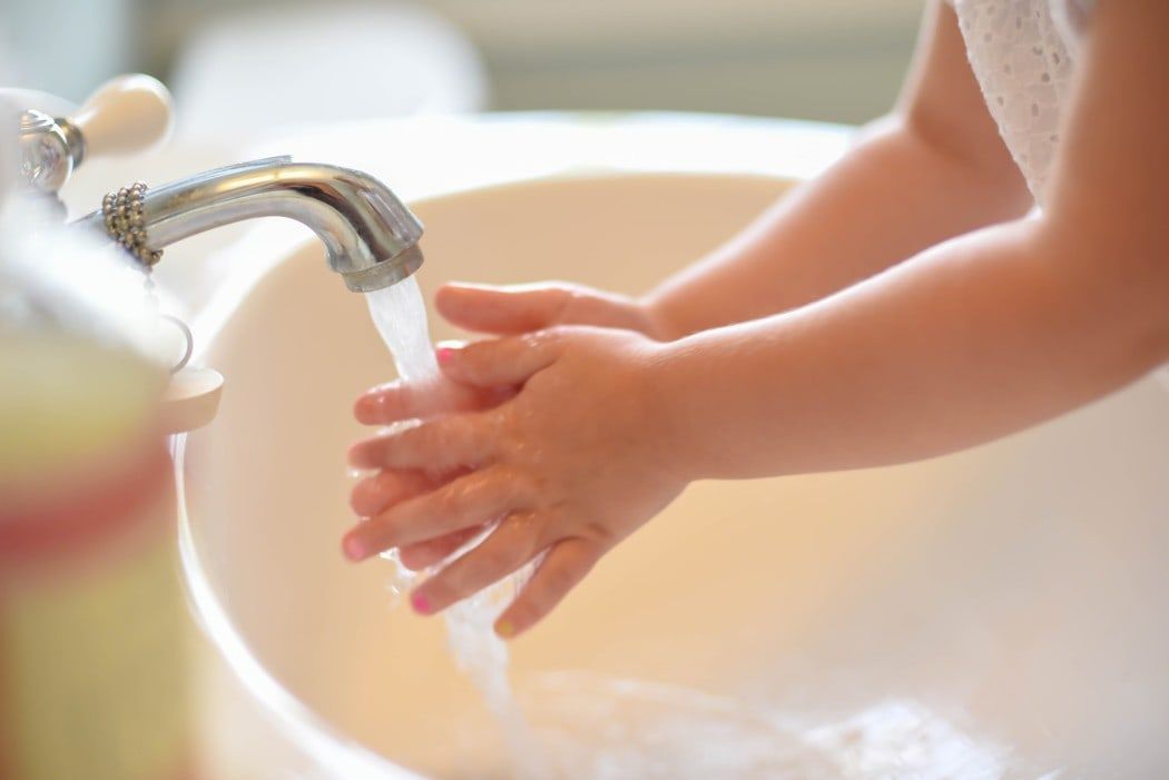 A child is washing their hands in a bathroom sink.