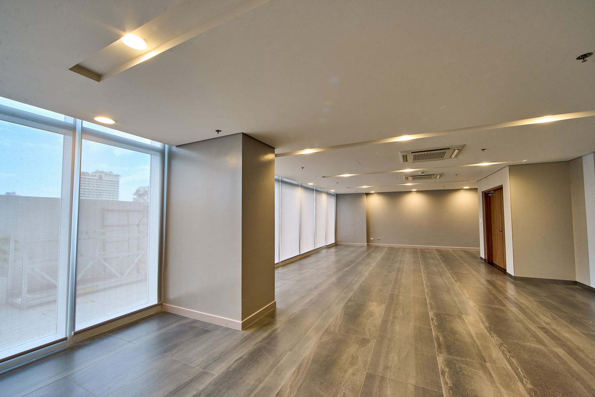 An empty room with a lot of windows and a wooden floor.