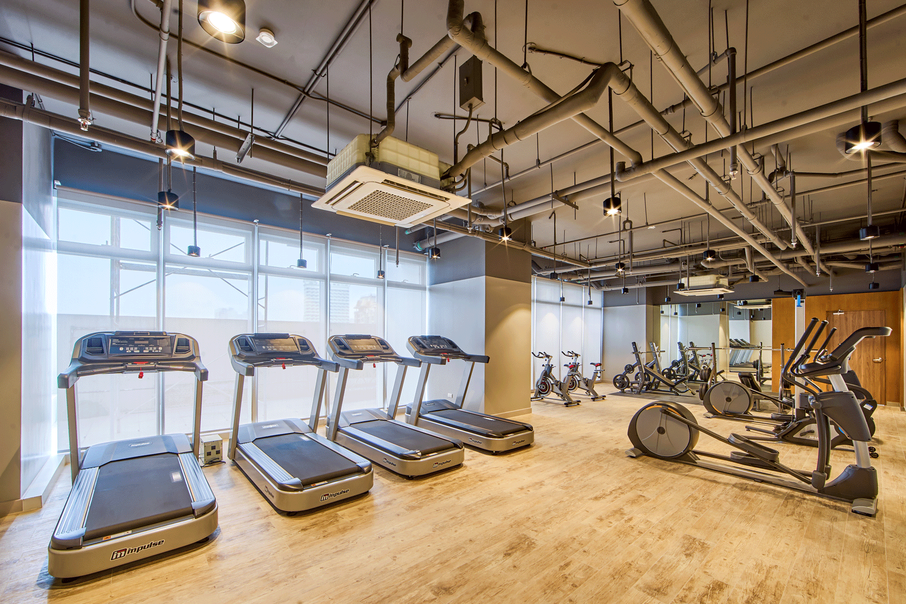 Modern fitness center at Connor Serviced Residences Manila with treadmills and cardio equipment facing panoramic windows