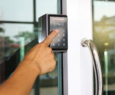 Finger pressing a keypad on a glass door access reader