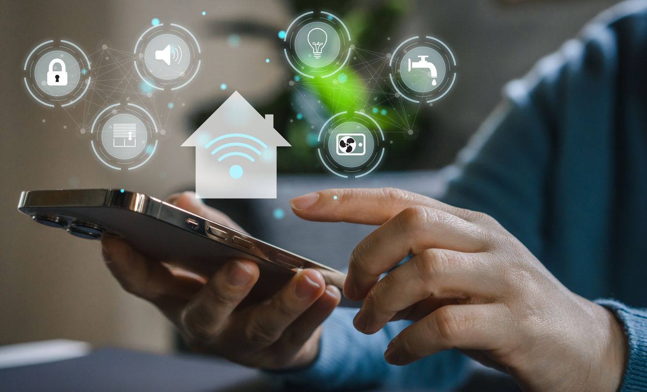 Hands using a smartphone with floating smart home icons in the background