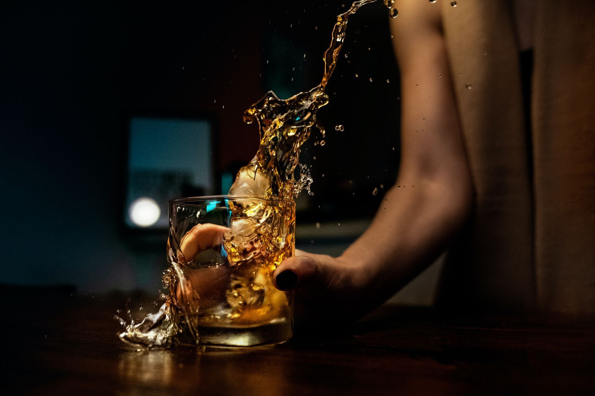 alcohol with whiskey being splashed down onto a table