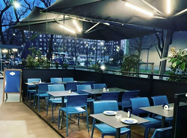 Un ristorante con sedie blu e tavoli sotto gli ombrelloni