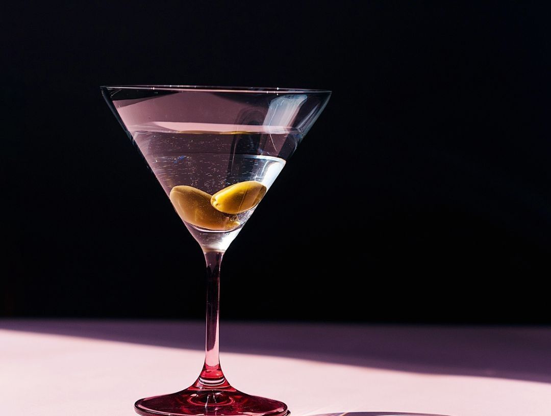 Un bicchiere da martini con un'oliva dentro è su un tavolo.