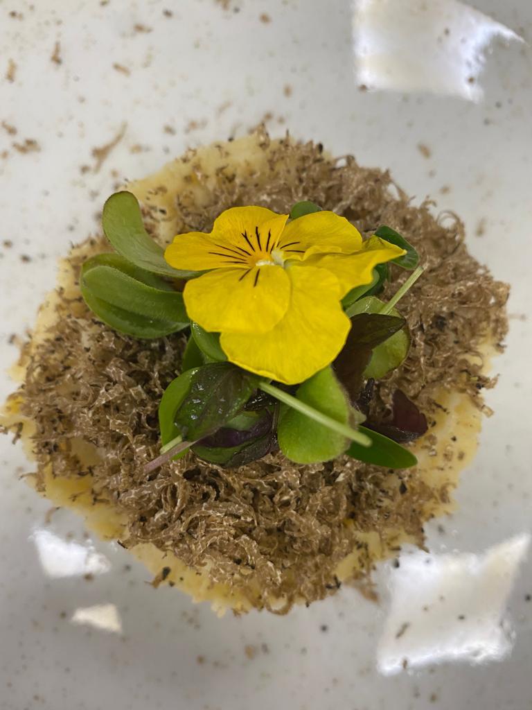 Un primo piano di un piatto di cibo con un fiore giallo sopra.