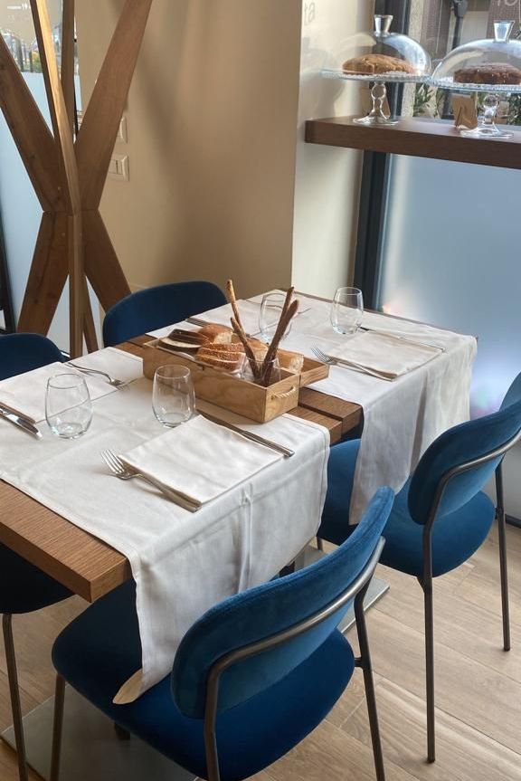 Un tavolo con una tovaglia bianca e sedie blu in un ristorante.