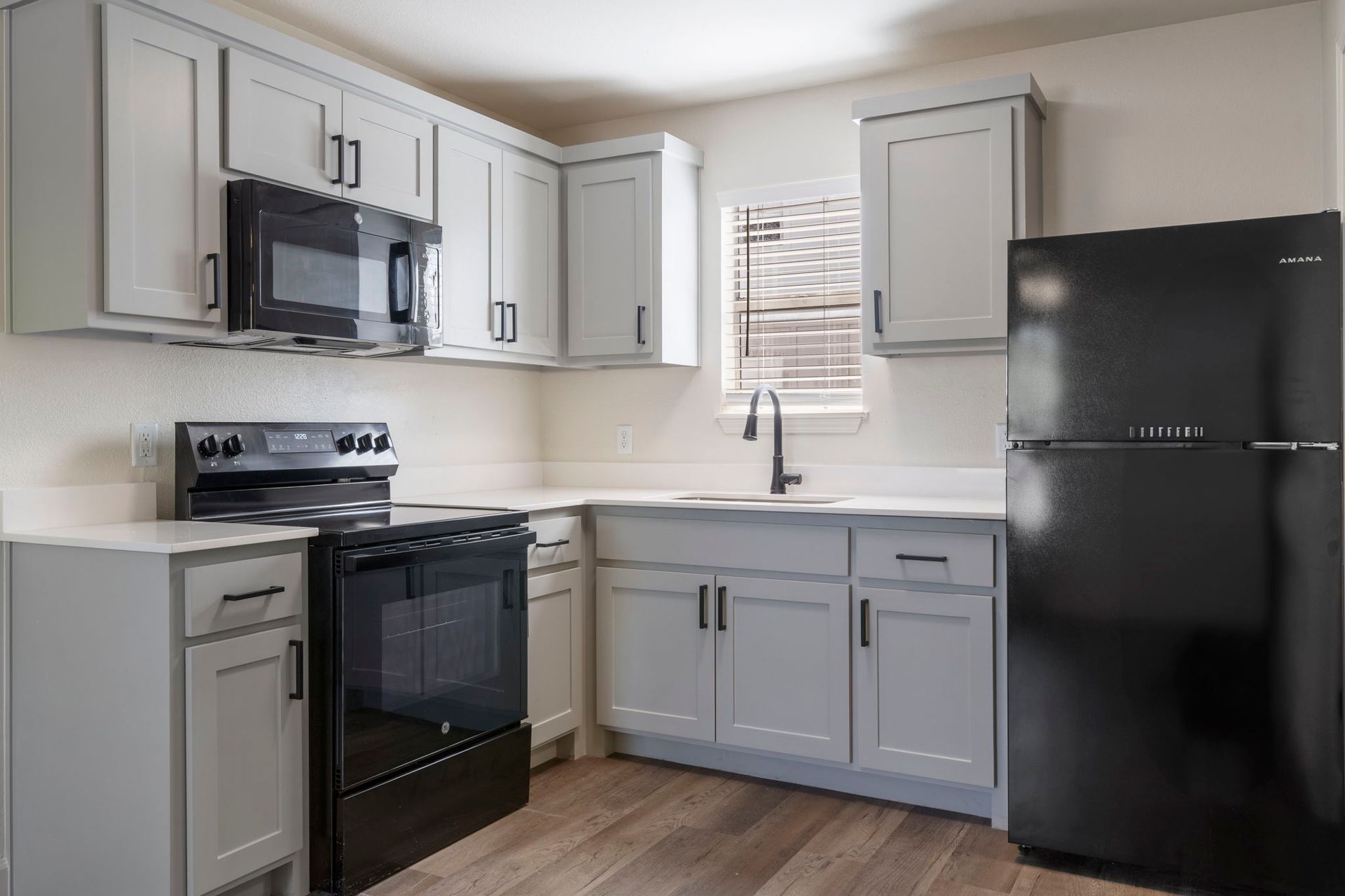 A kitchen with white cabinets , black appliances , and a black refrigerator.