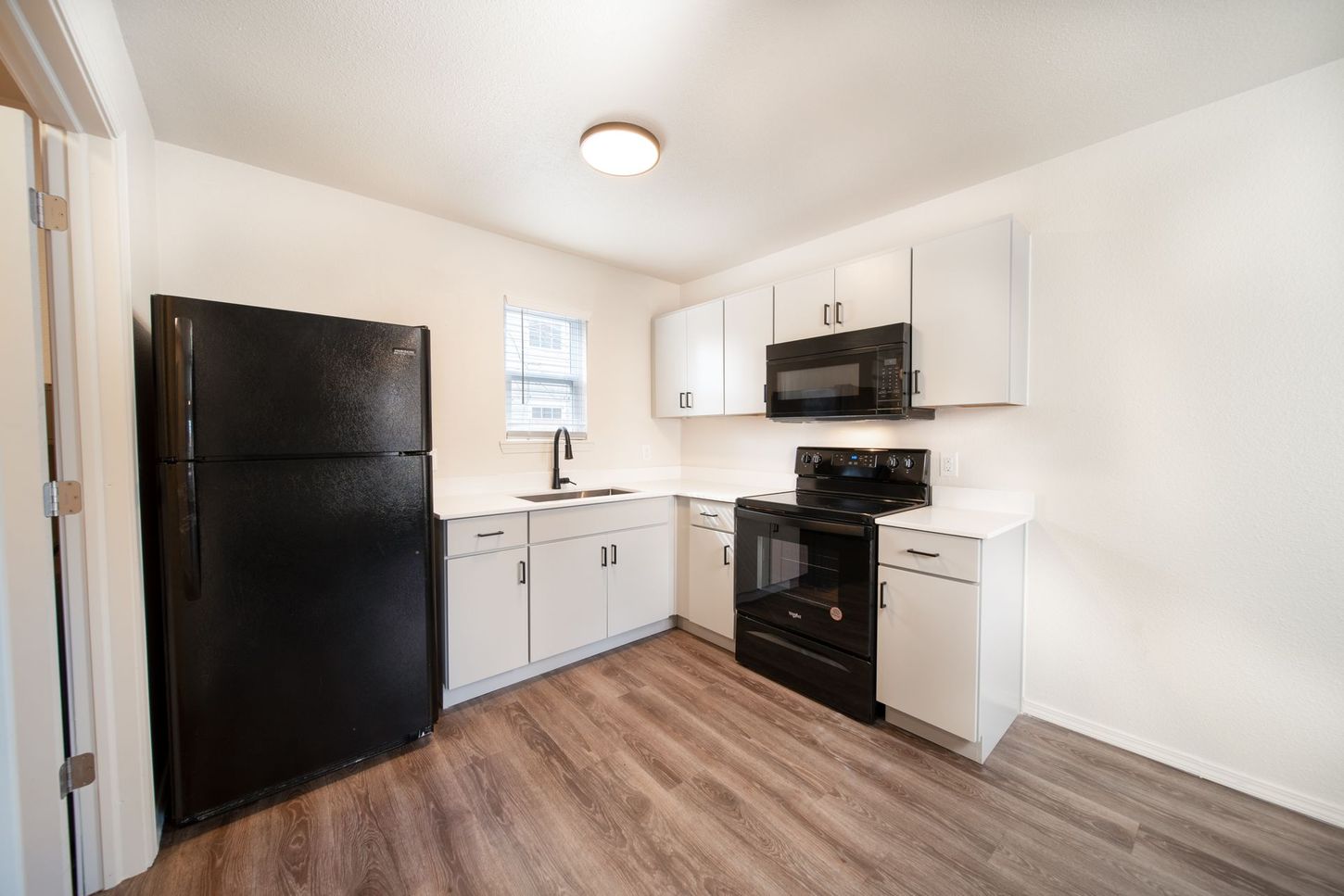 A kitchen with a black refrigerator , black stove , and white cabinets.