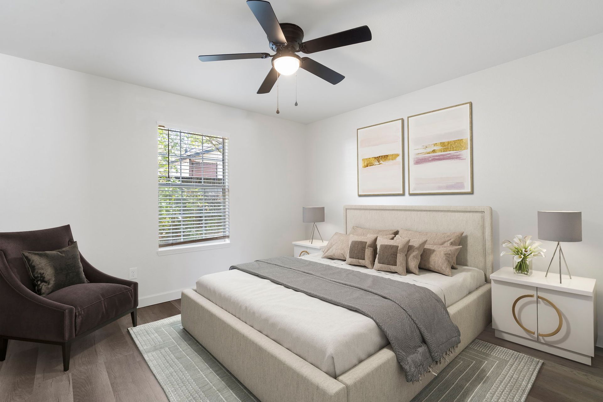 A bedroom with a bed , chair , nightstand and ceiling fan.