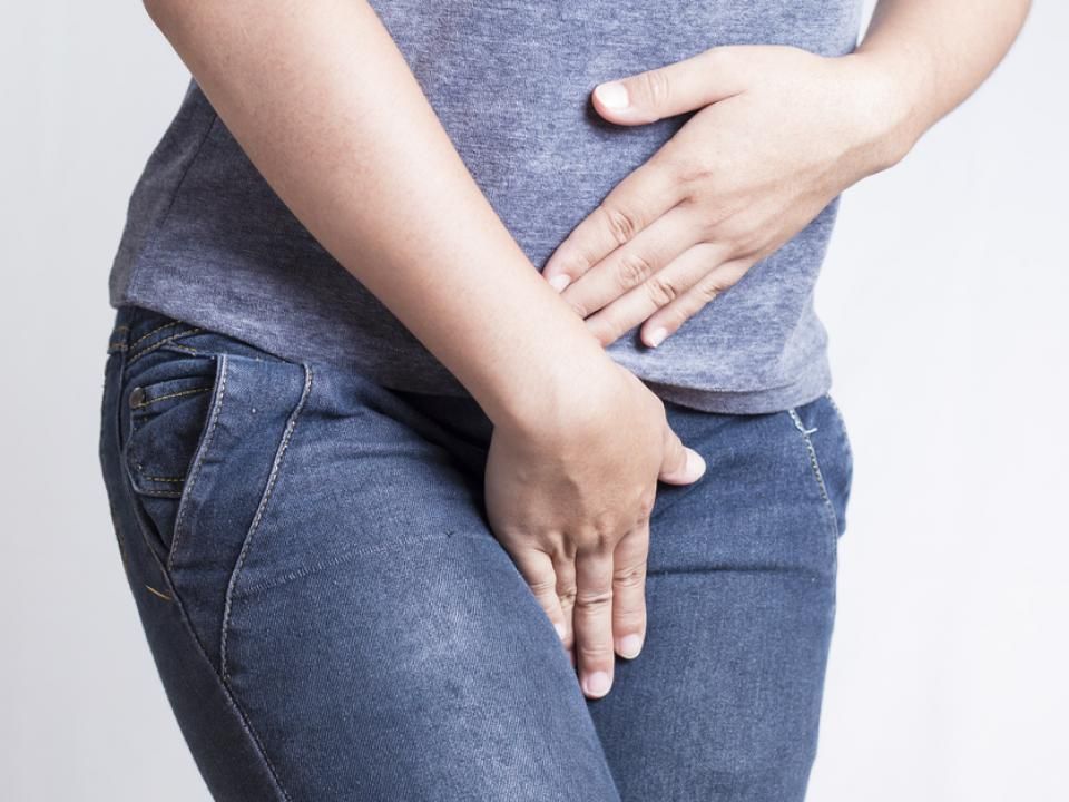 Man kissing a woman's forehead while hugging her in a field of yellow flowers.