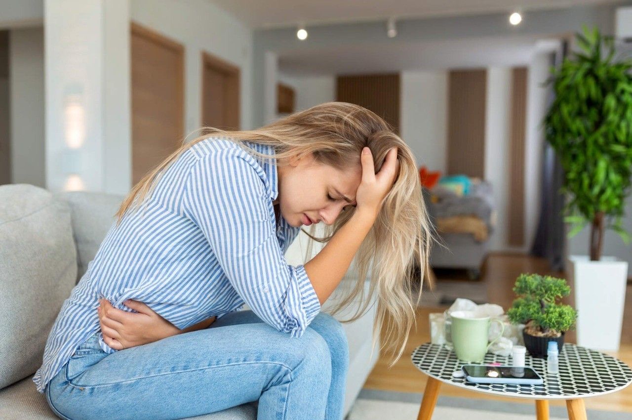 Man with curly hair smiling outdoors, wearing a gray sweater.