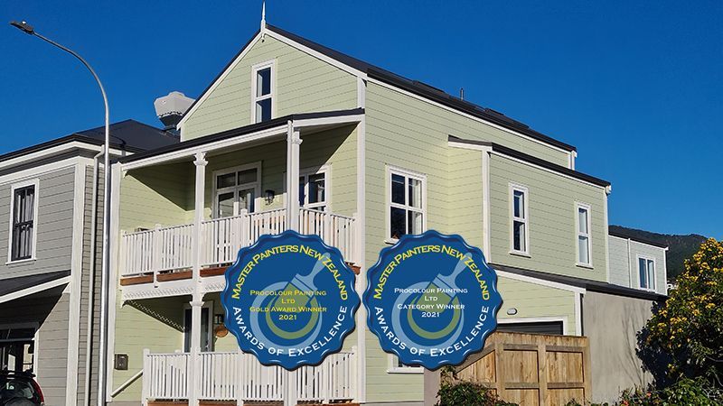 A light green house with white trim and a balcony, with two 