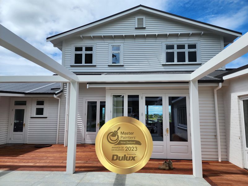 White house with a wooden deck and pergola, Master Painter award from Dulux.