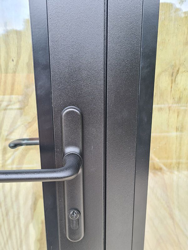 Black door handle on a textured black door frame, close-up with a keyhole.