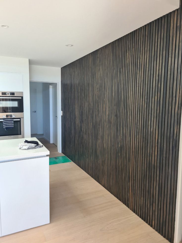 Dark wood textured accent wall in a modern kitchen.