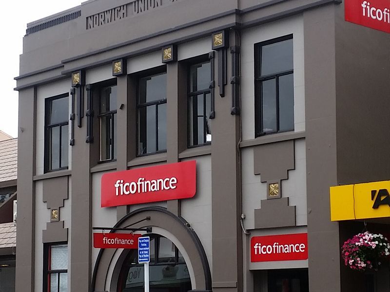 A two-story building with a blue facade and yellow awning. Outdoor seating visible.