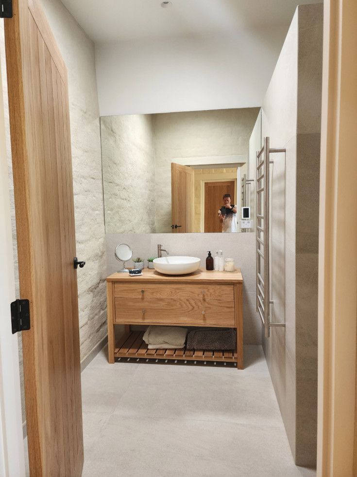 Bathroom with wooden vanity, large mirror, and open door. Towel rack on the right wall.