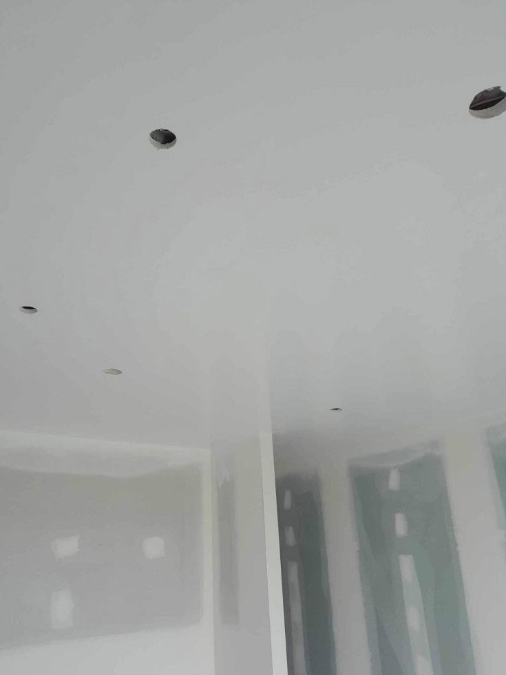 White ceiling with recessed lighting fixtures in a room under construction.