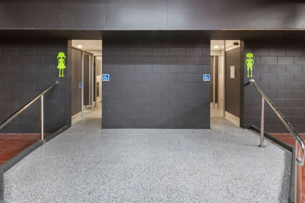 Public restroom entrance with ramp, accessible stall, female and accessibility symbols.