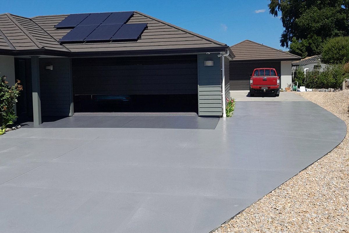 Two-story house with a white garage door, three upstairs windows with dark shades, and a paved driveway.