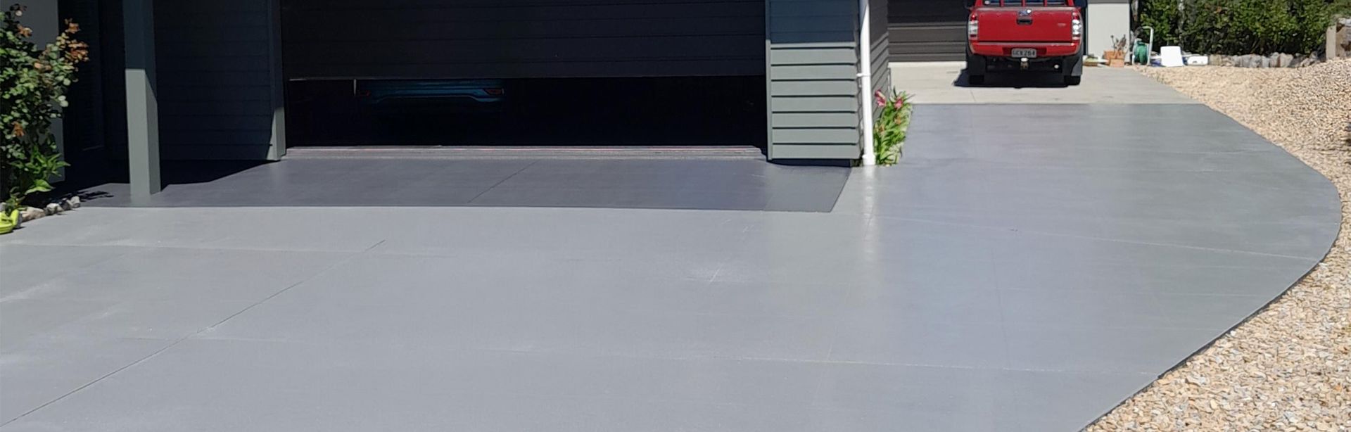 Gray painted driveway leads to a garage. A red pickup truck is parked in the driveway.