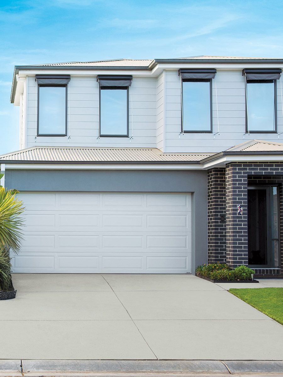Two-story house with a white garage door, three upstairs windows, and a driveway.