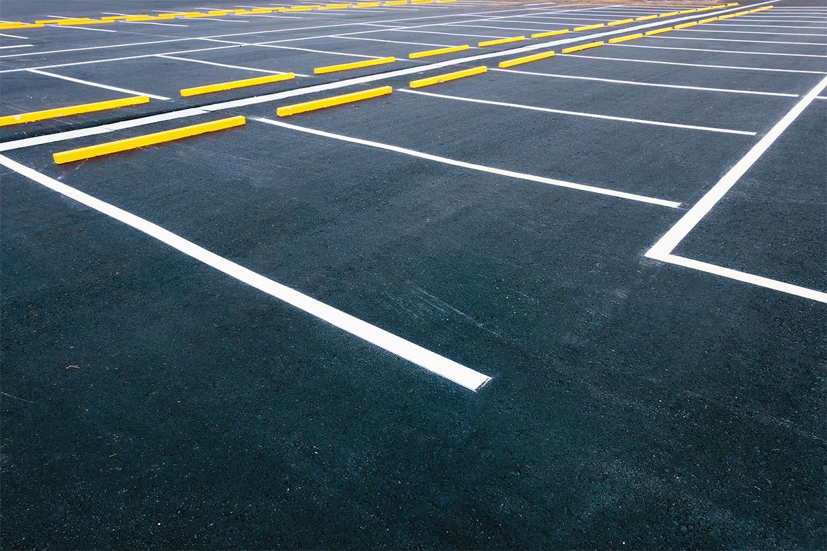 Parking lot with white painted lines and yellow parking space bumpers on dark asphalt.