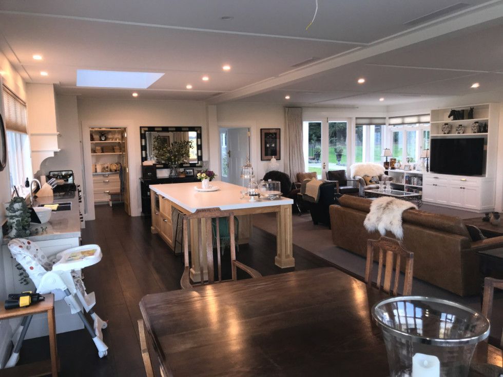 Spacious open-plan kitchen and living room with island, dark wood floors, and neutral tones.