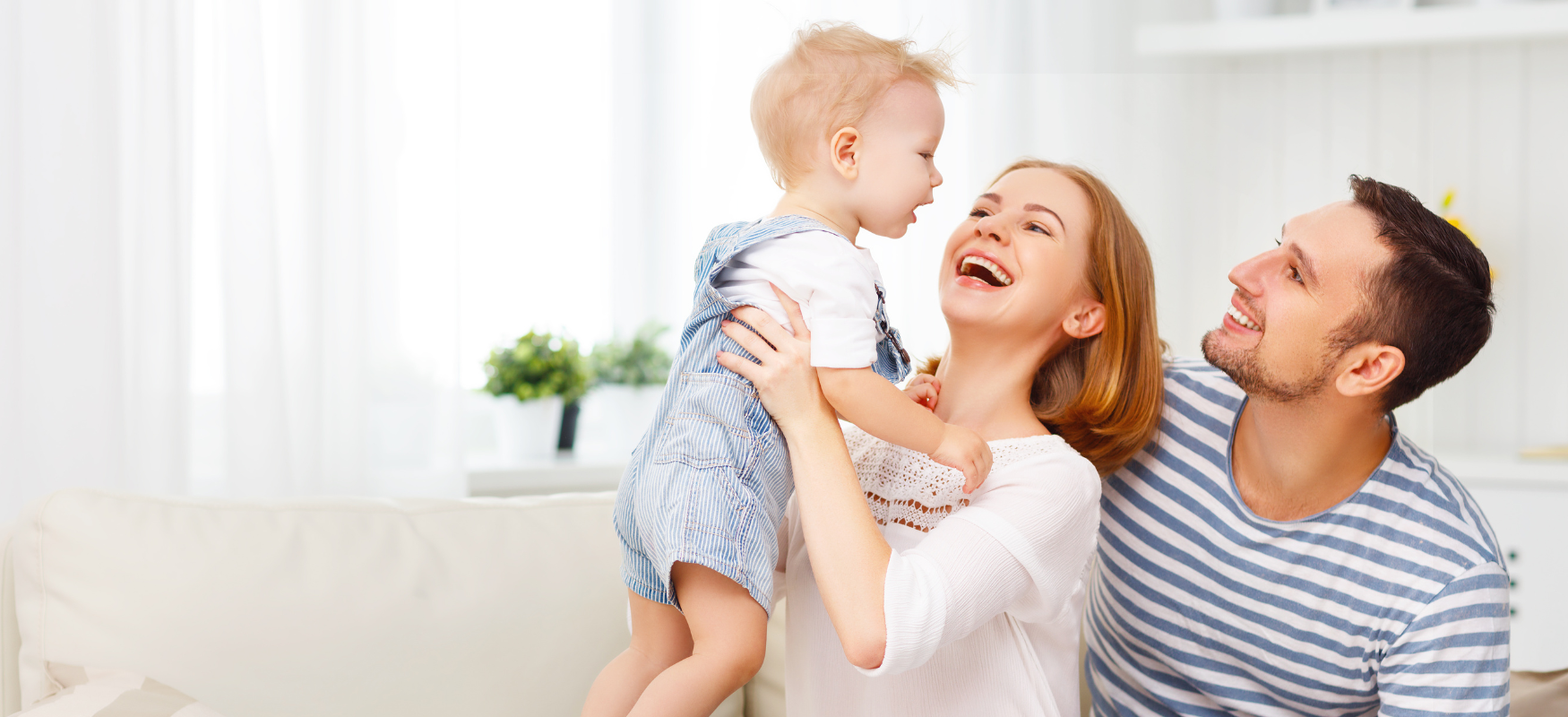 A family is sitting on a couch holding a baby in their arms.