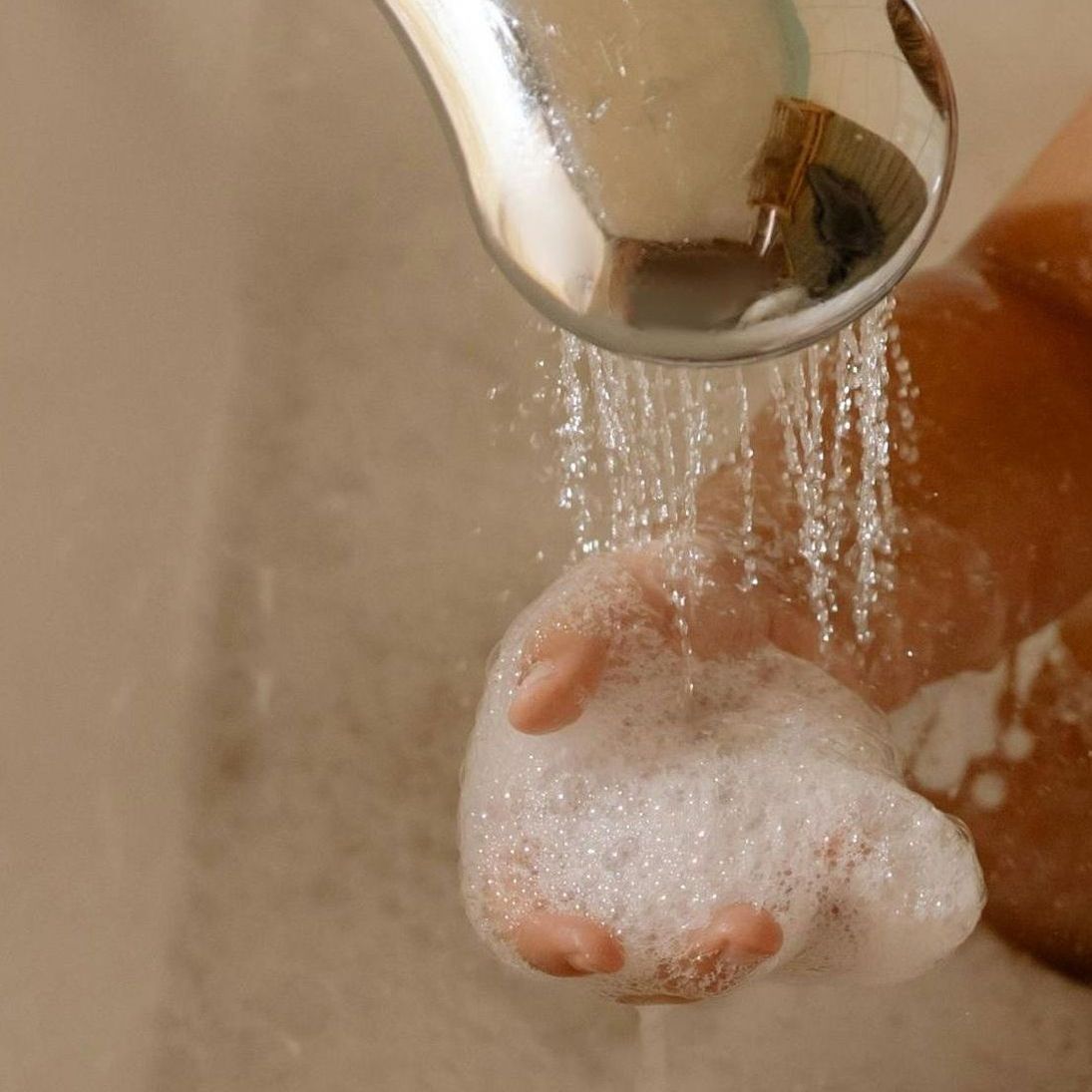 A person is washing their hands in a sink with soap and water.