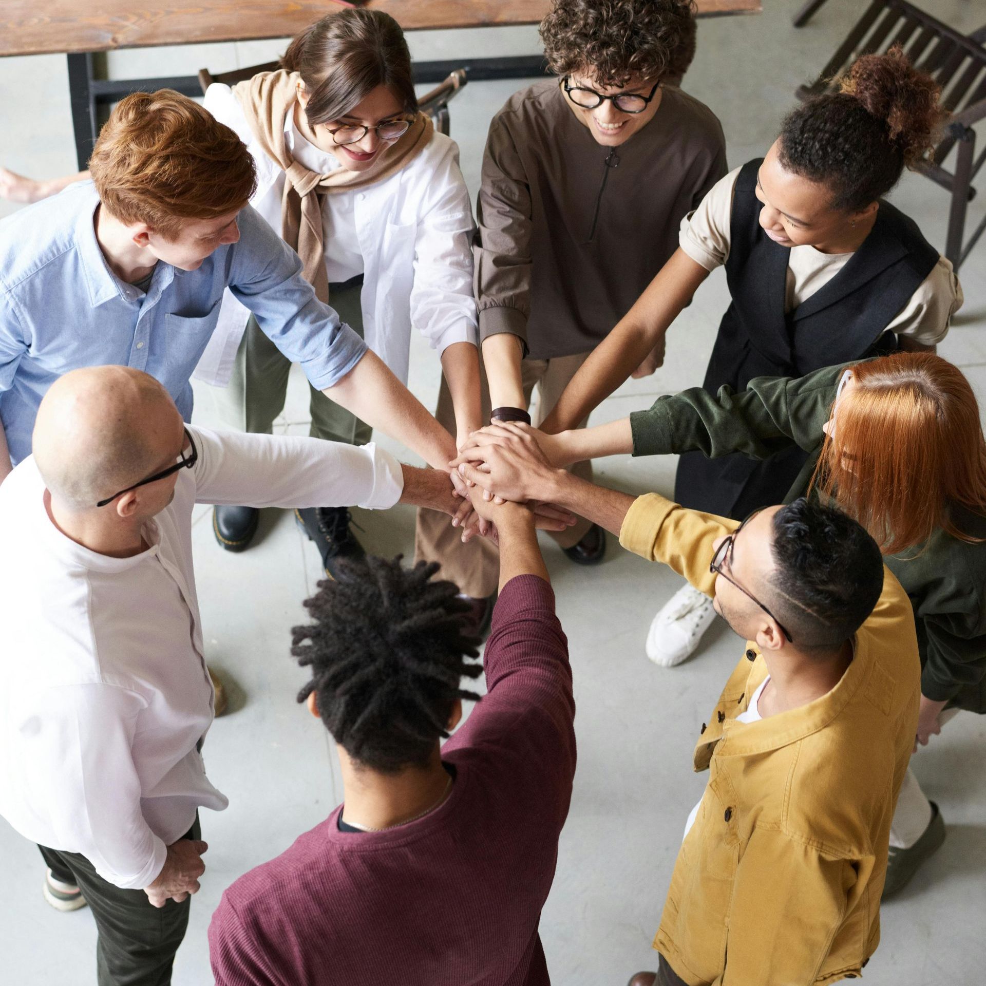 A group of people are putting their hands together in a circle.