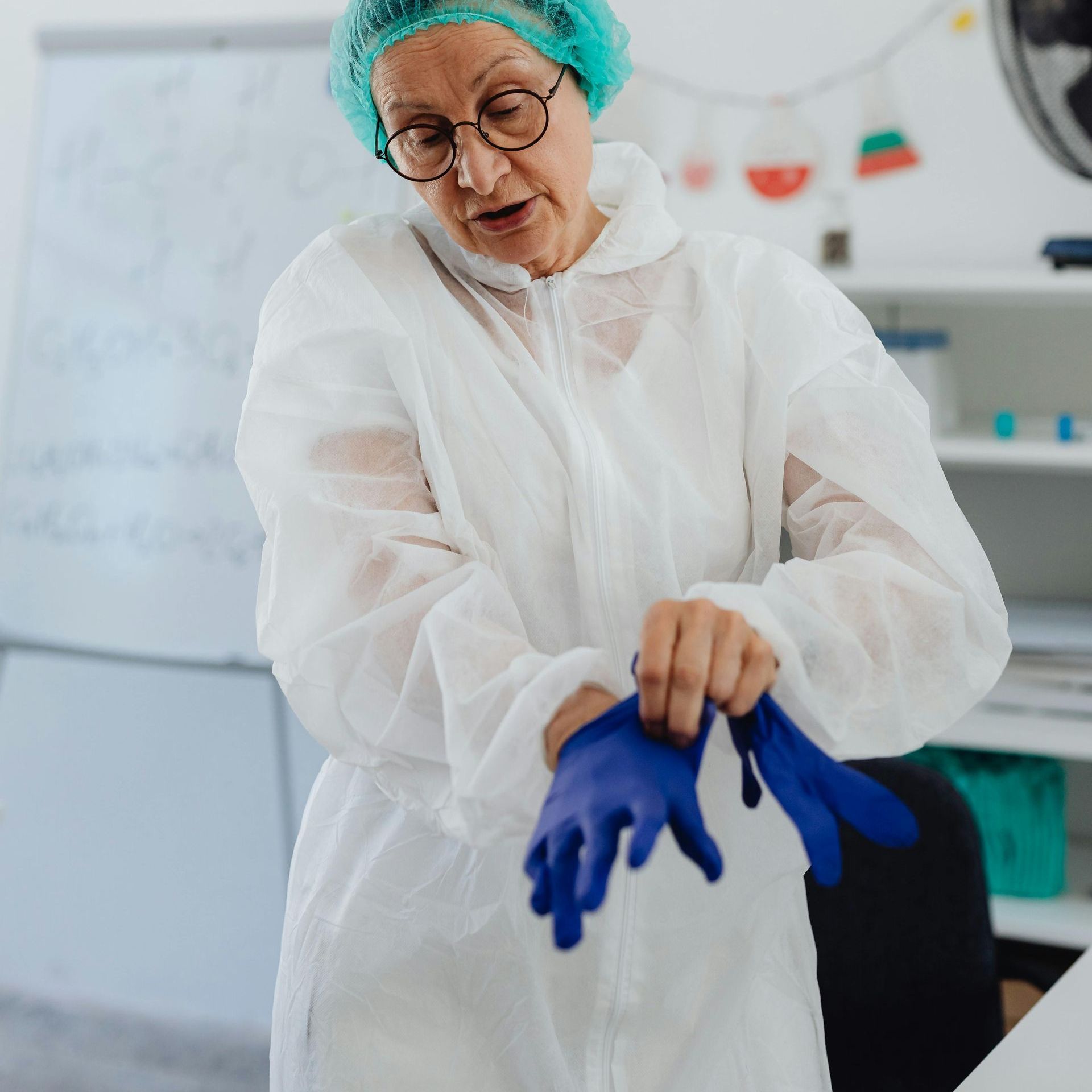 A woman wearing a white coverall and blue gloves