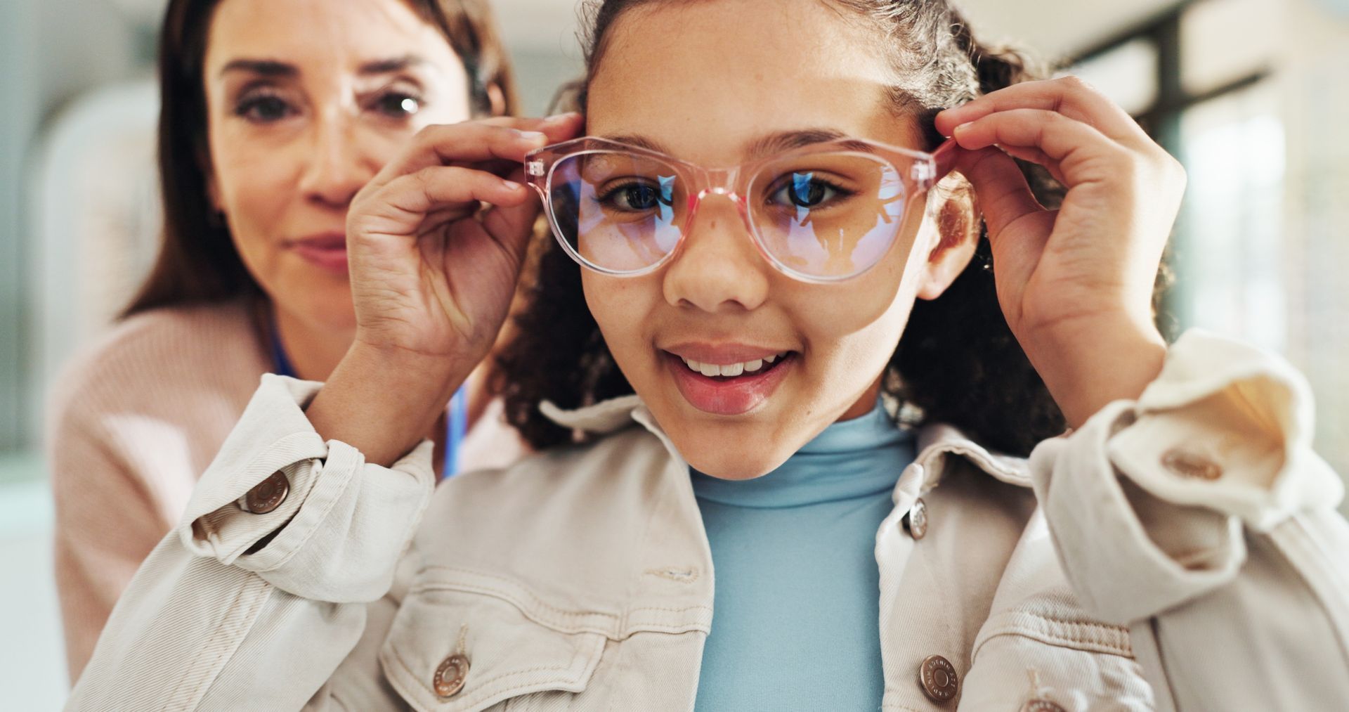 Woman adjusts eyeglasses on a smiling child