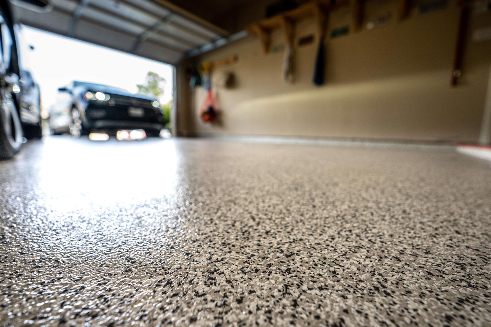 Close-up view of a garage floor with a speckled, epoxy coating, with a car parked inside.