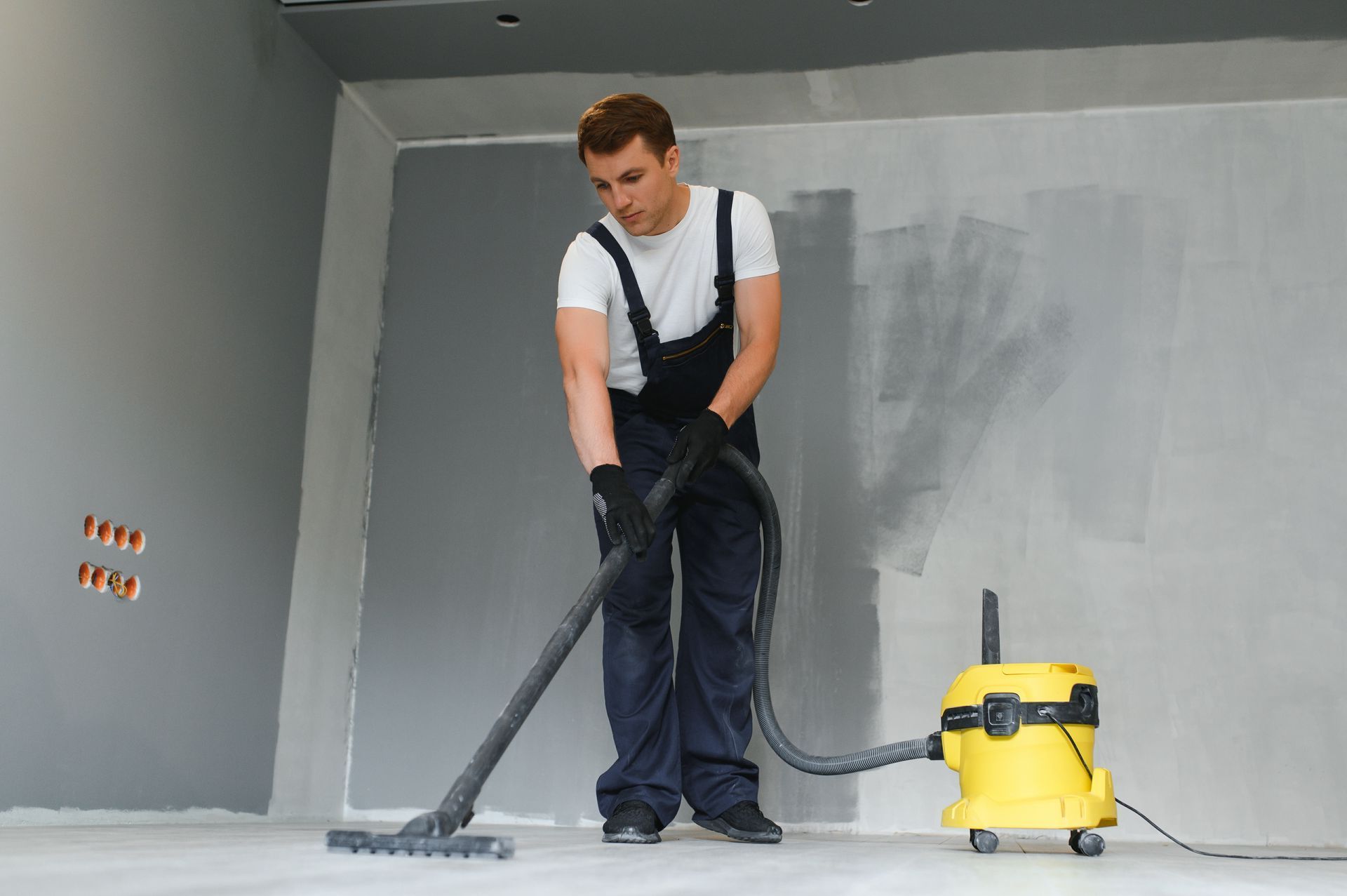 A man is cleaning the floor with a vacuum cleaner.