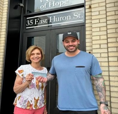 A man and a woman are standing in front of a building on East Huron Street.