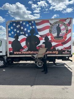 A man is standing in front of a truck with an american flag on it.