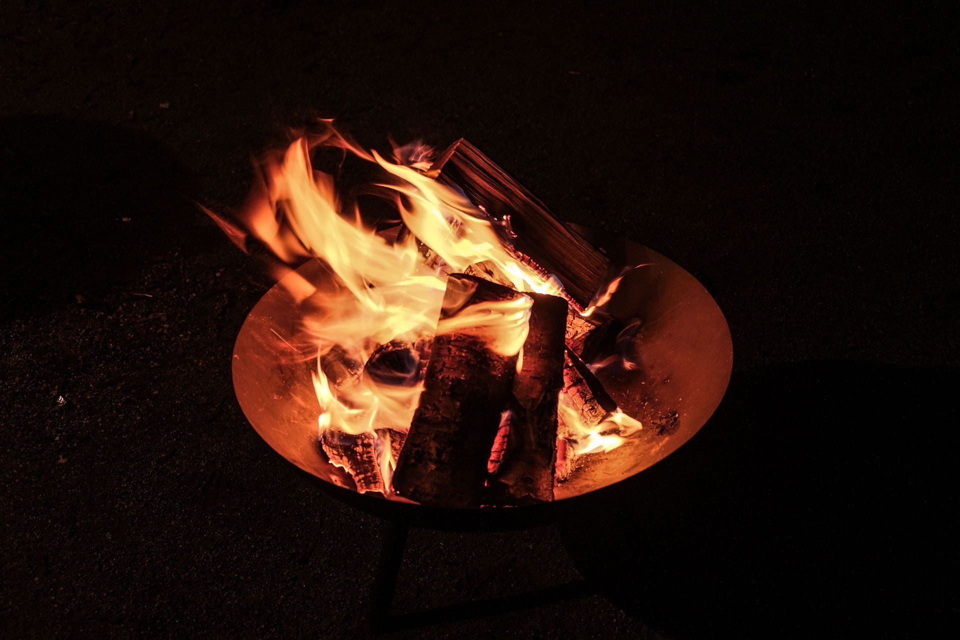 Burning logs in a round fire pit at night