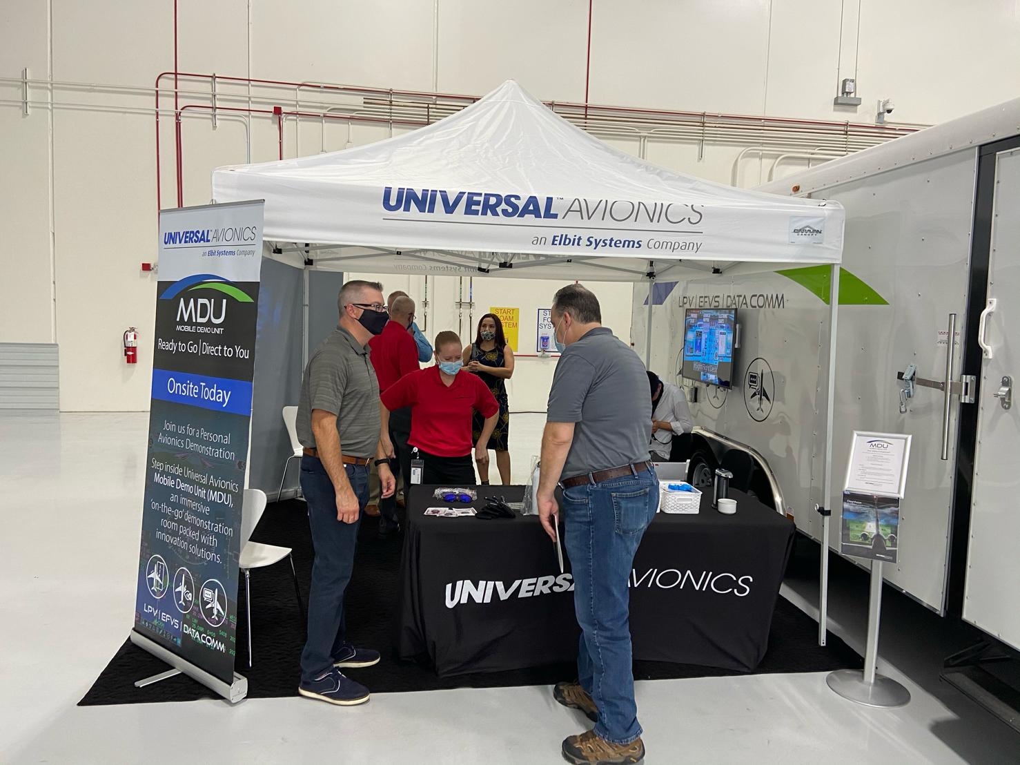 A group of people are standing around a table under a tent.